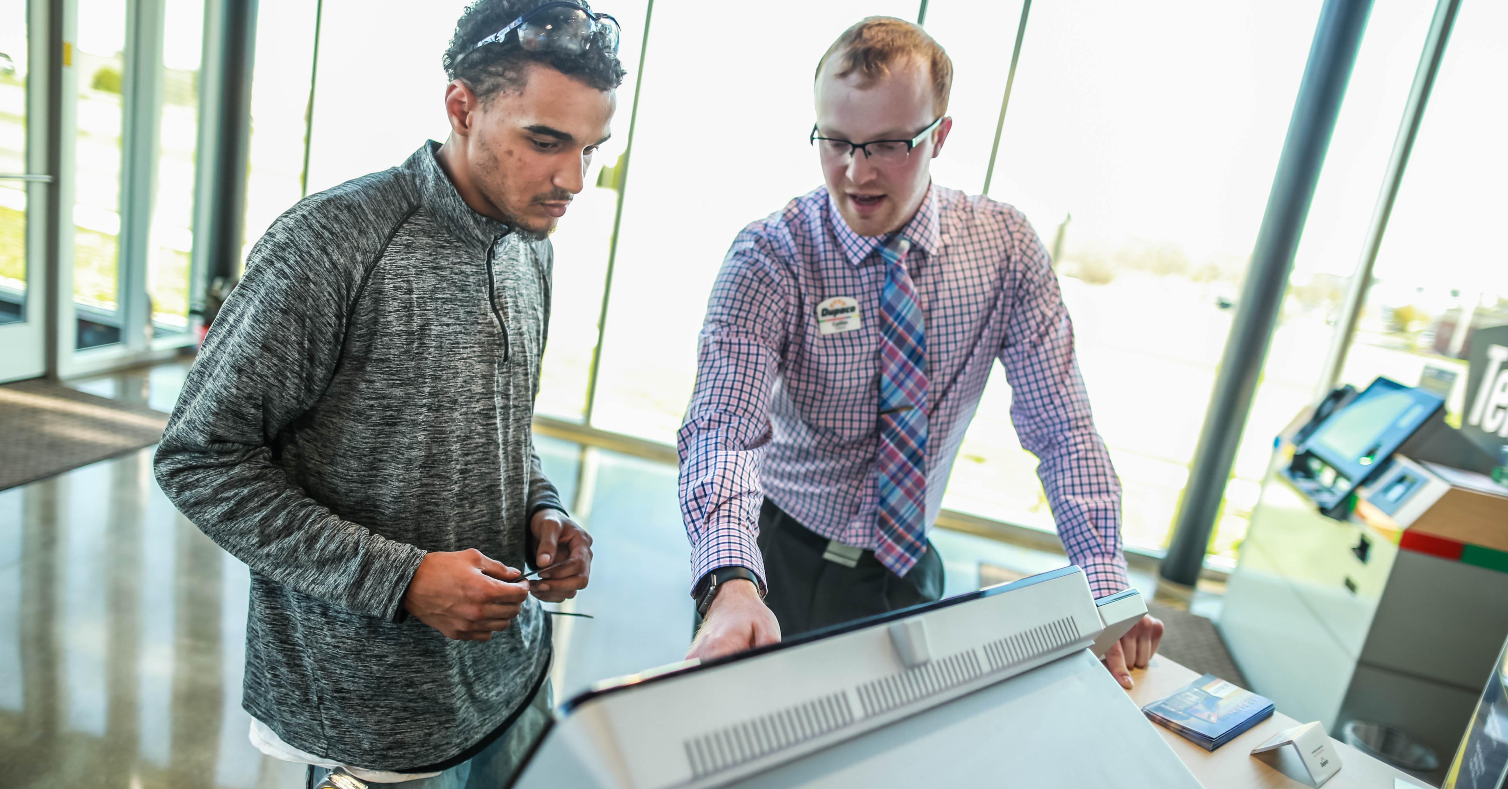 Shortly after the opening of the San Marnan Learning Lab in Waterloo, Iowa, Dupaco member Donovan Miles (left) uses the Interactive Teller Machine with the help of Dupaco’s Collin Olson. (G. Brown photo)